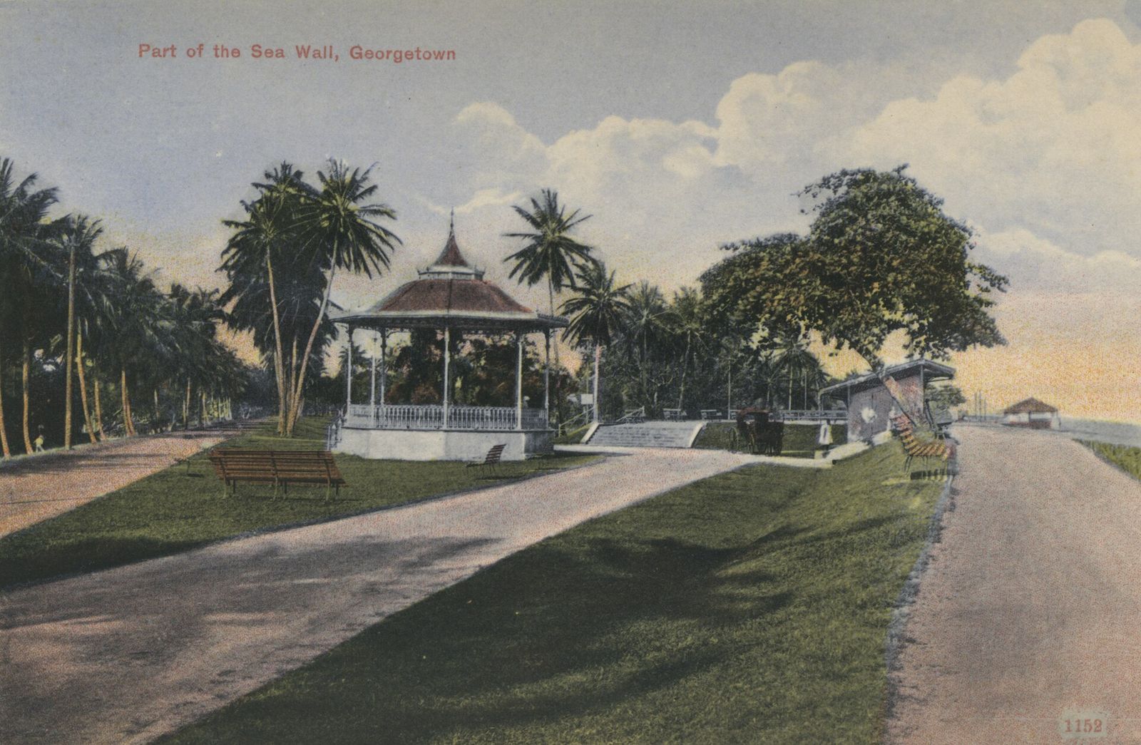 The sea wall promenade at Georgetown around 1910: a bandstand among palms and shade trees, benches, and the wall road running towards the sea