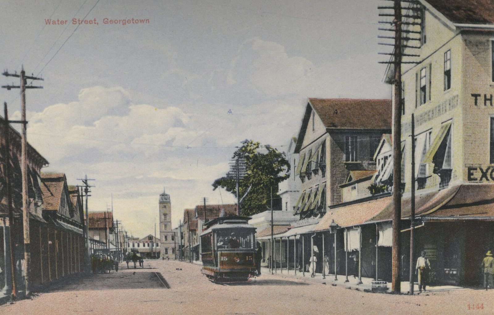 Water Street, Georgetown, around 1910: an electric tram in the roadway between timber shopfronts with awnings, carts and pedestrians, a tower at the far end